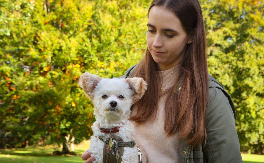 Lady and small fluffy white dog sitting in the park