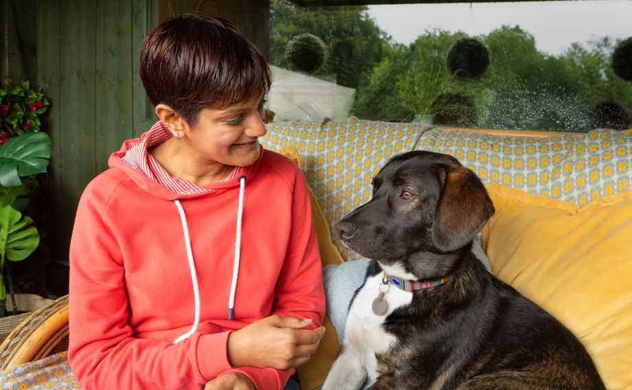 Lady in red hoodie sitting on the sofa with her black dog